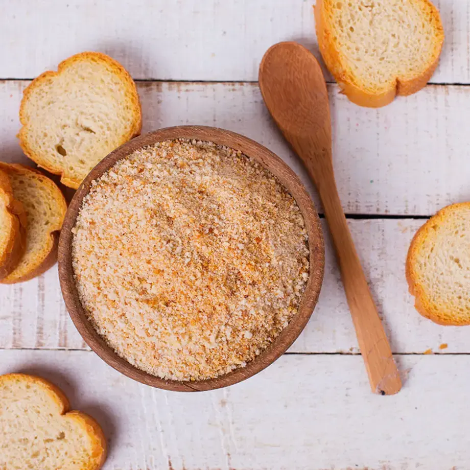 Slices of stale bread and a bowl of breadcrumbs.