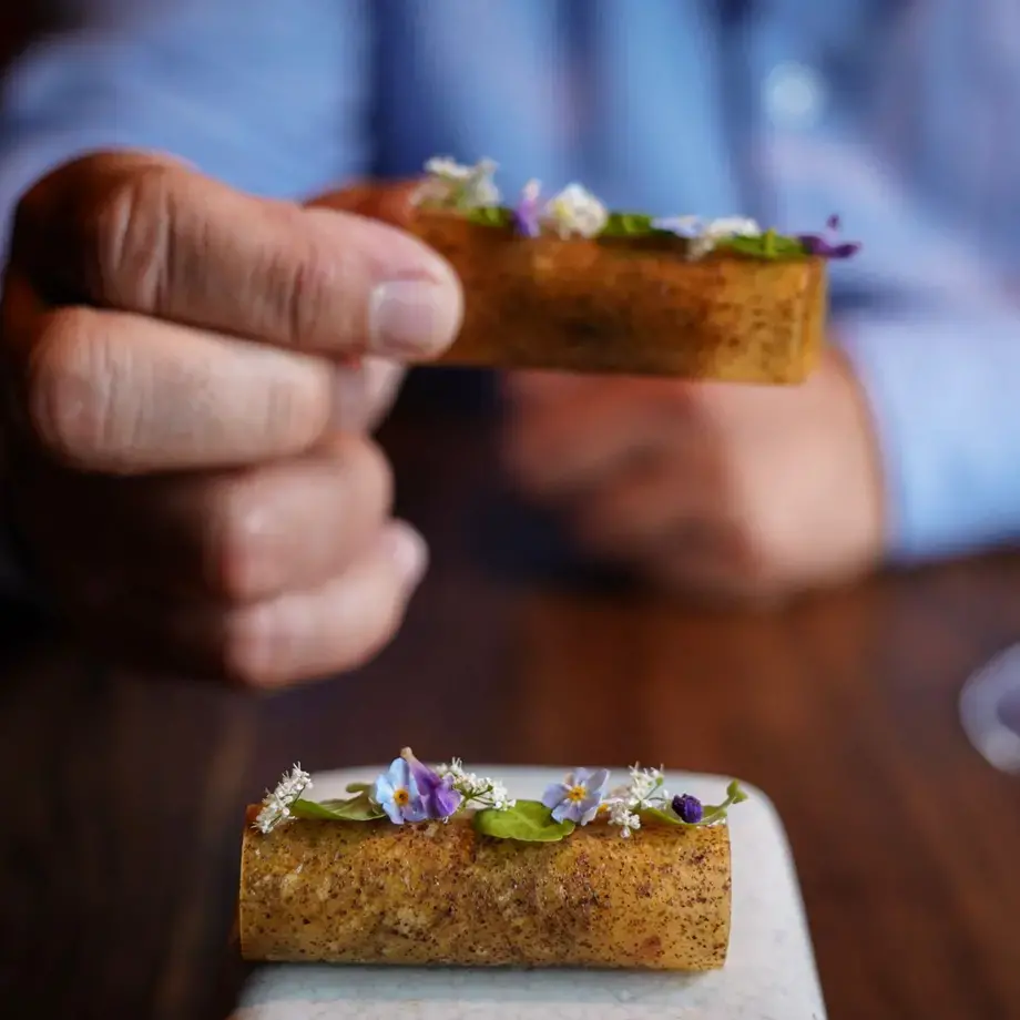 a hand picking up an amuse bouche in a fine dining restaurant