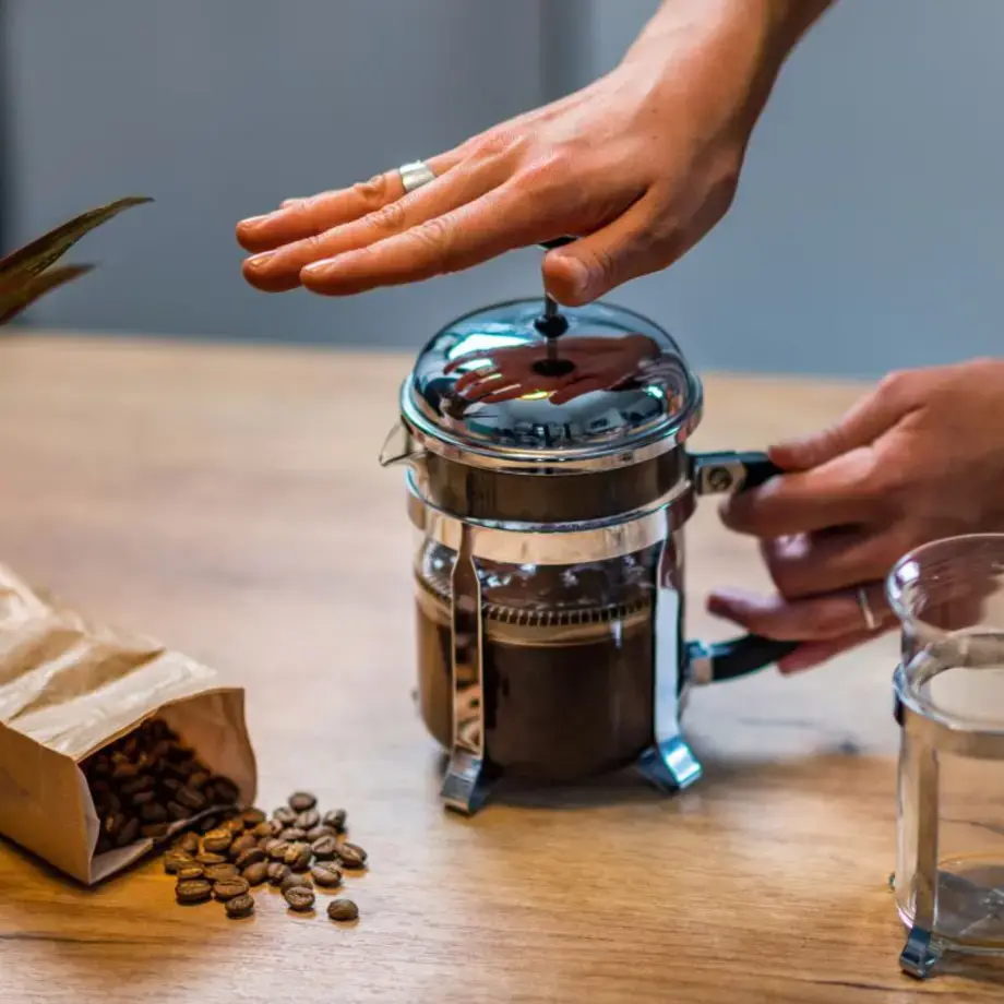 A woman using a French press to brew coffee.