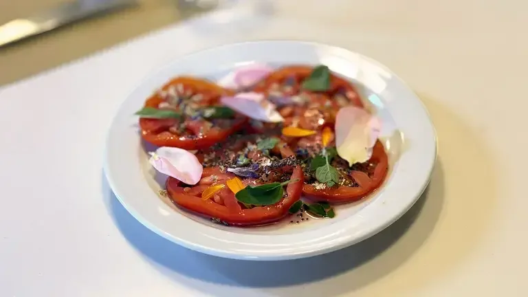 Tomato carpaccio with mountain flowers plated