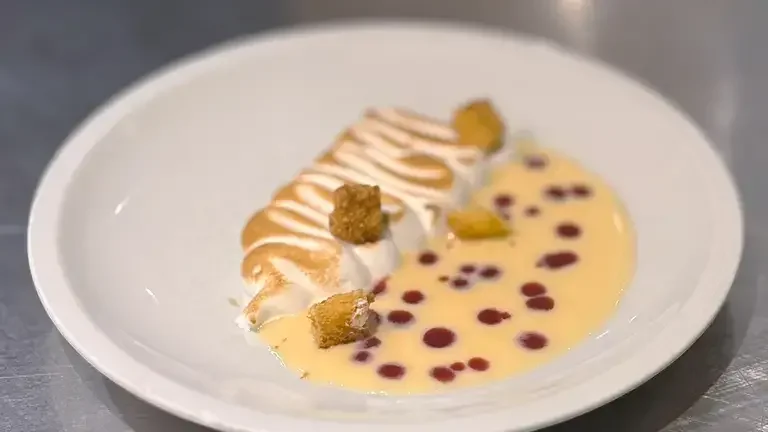 Meringue, pandoro and red berry coulis plated