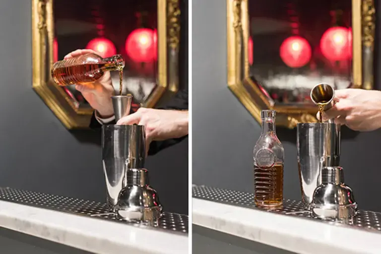 a hand measuring amaretto into a jigger