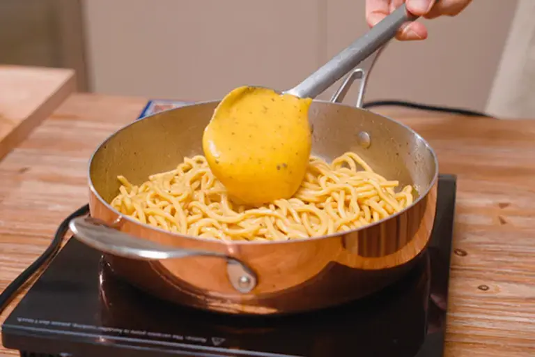 Mixing pasta and egg sauce for carbonara.