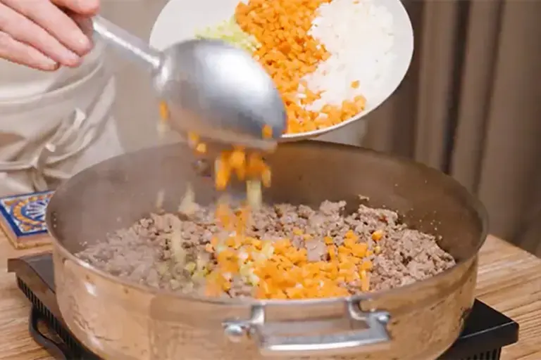 Adding chopped vegetables to the ragù.