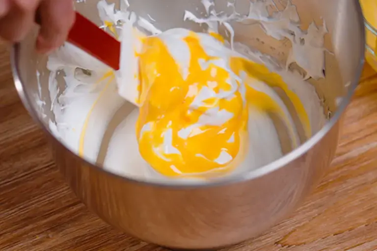 Incorporating yolks into the whipped whites.