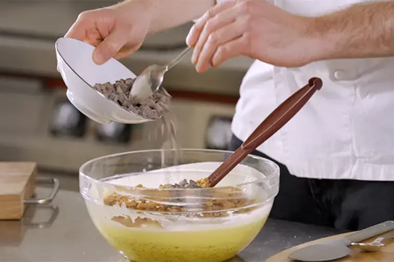 A chef pours chocolate into a mixing bowl.