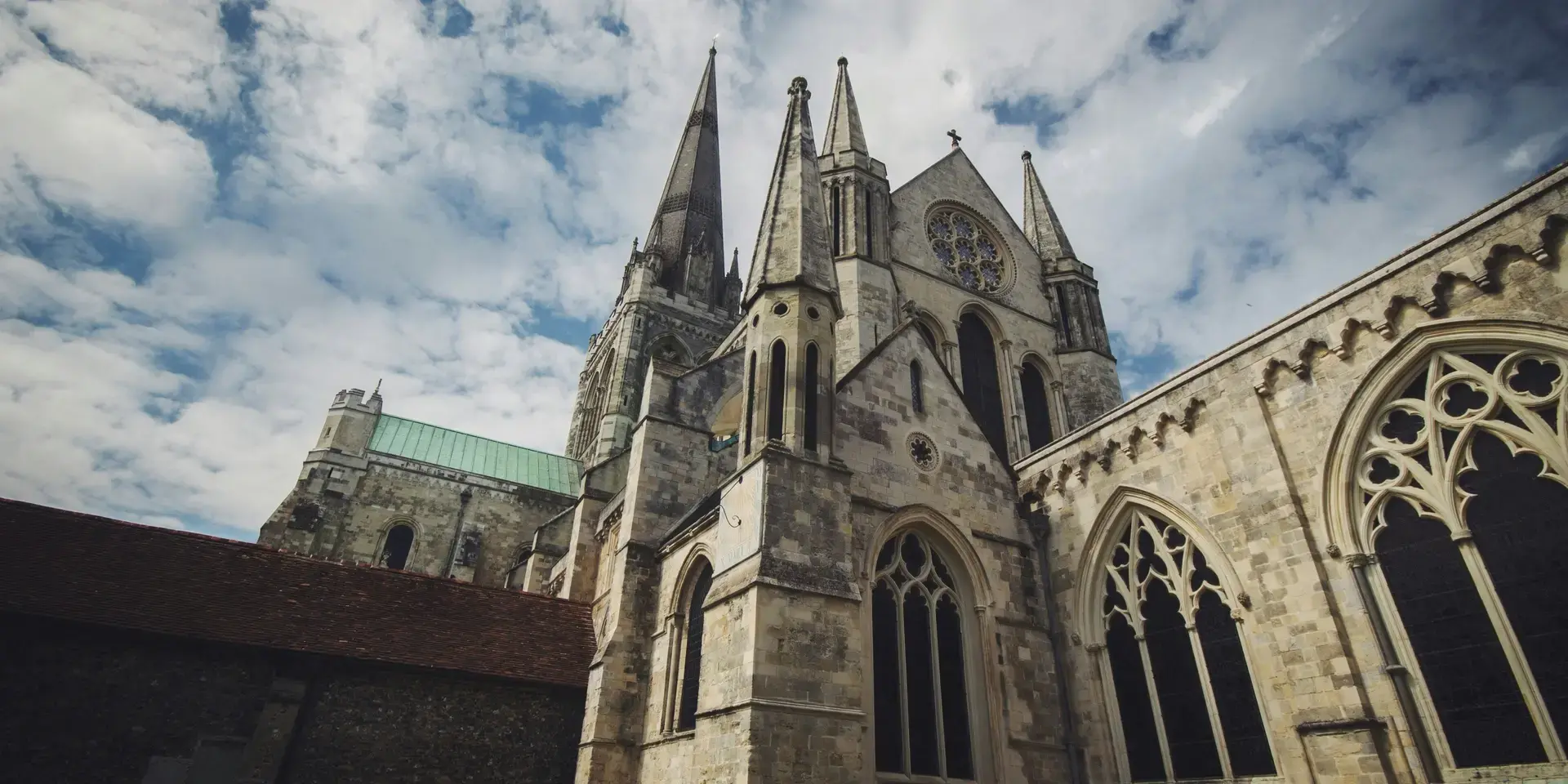 Gothic cathedral with spires and arches under a cloudy sky, showcasing intricate stonework and historic architecture
