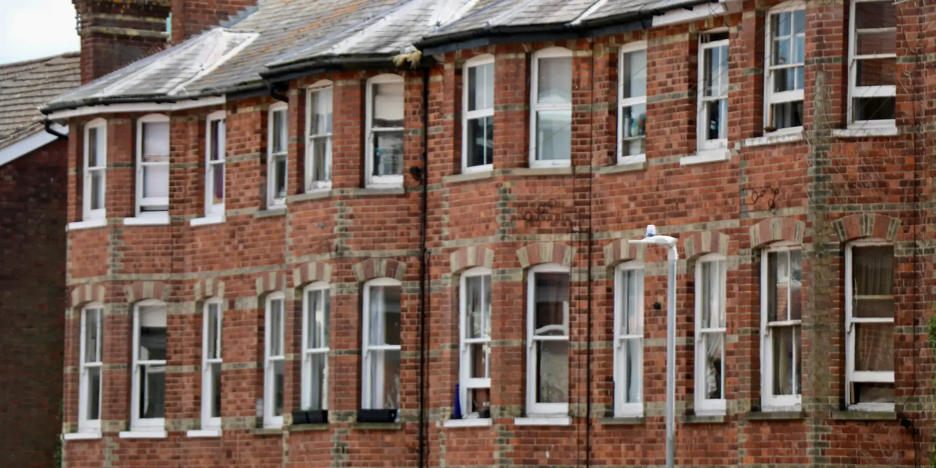 Brick apartment building with multiple windows and arched accents, under a cloudy sky