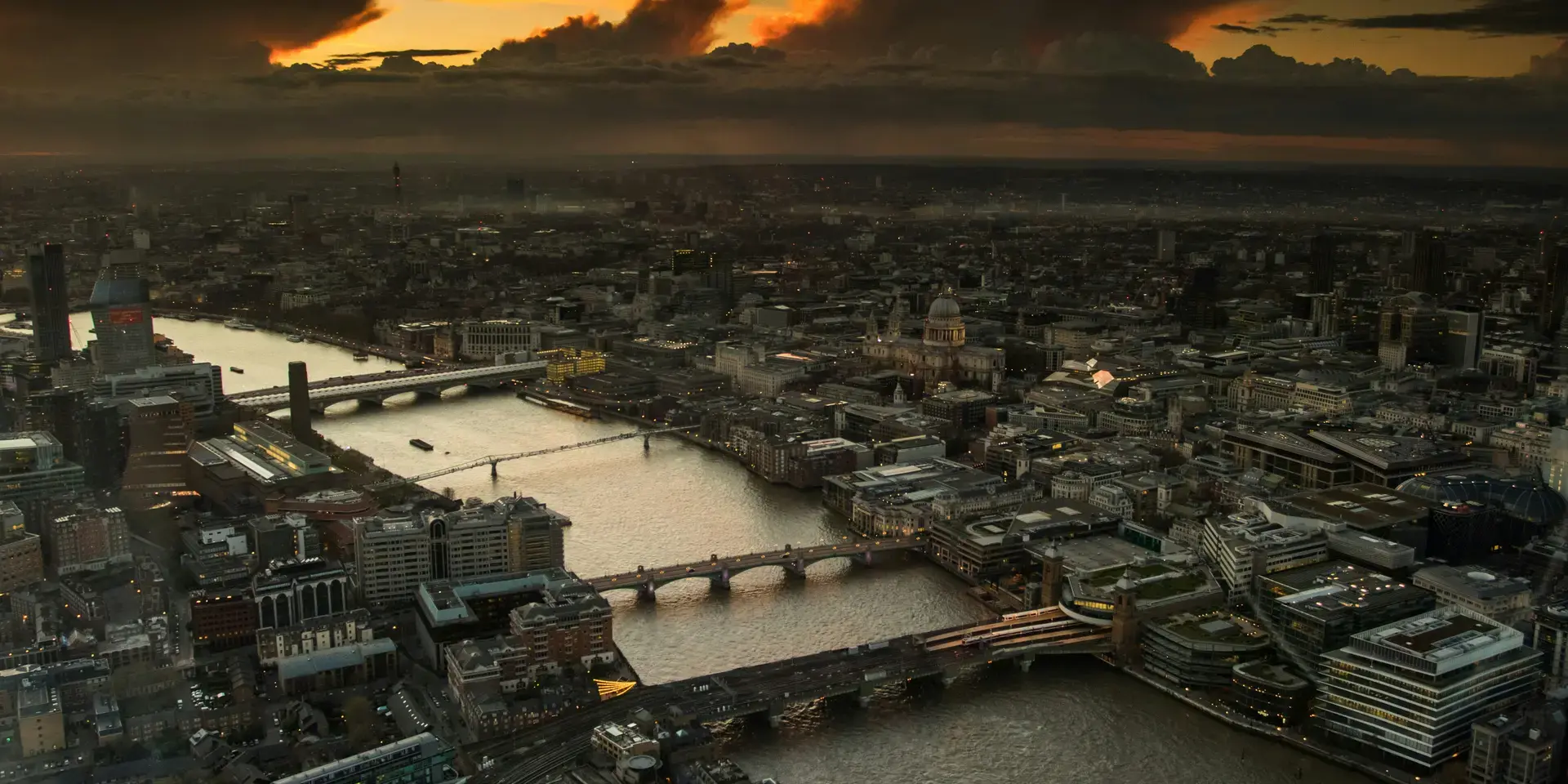 London skyline at sunset with Thames, bridges, St. Paul’s Cathedral, and dramatic clouds glowing in the evening light
