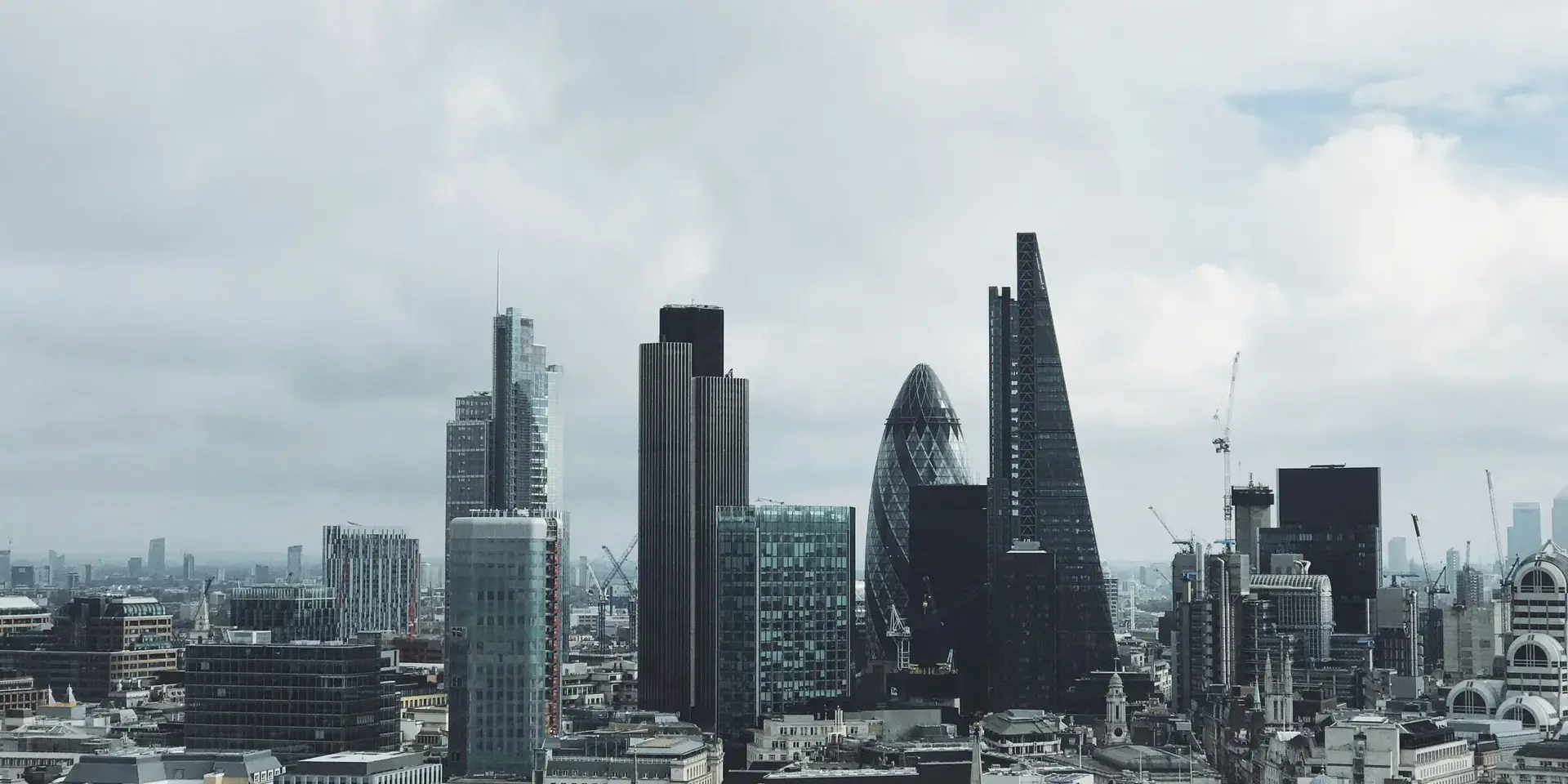 London’s iconic skyline with The Gherkin, The Cheesegrater, and modern skyscrapers rising under a cloudy sky