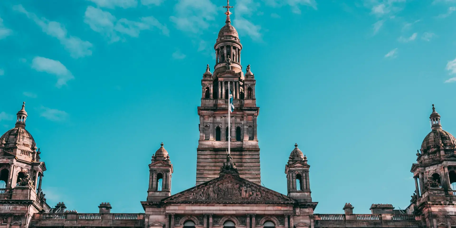 Ornate building with towers and sculptures, set against a bright blue sky, showcasing intricate architectural details