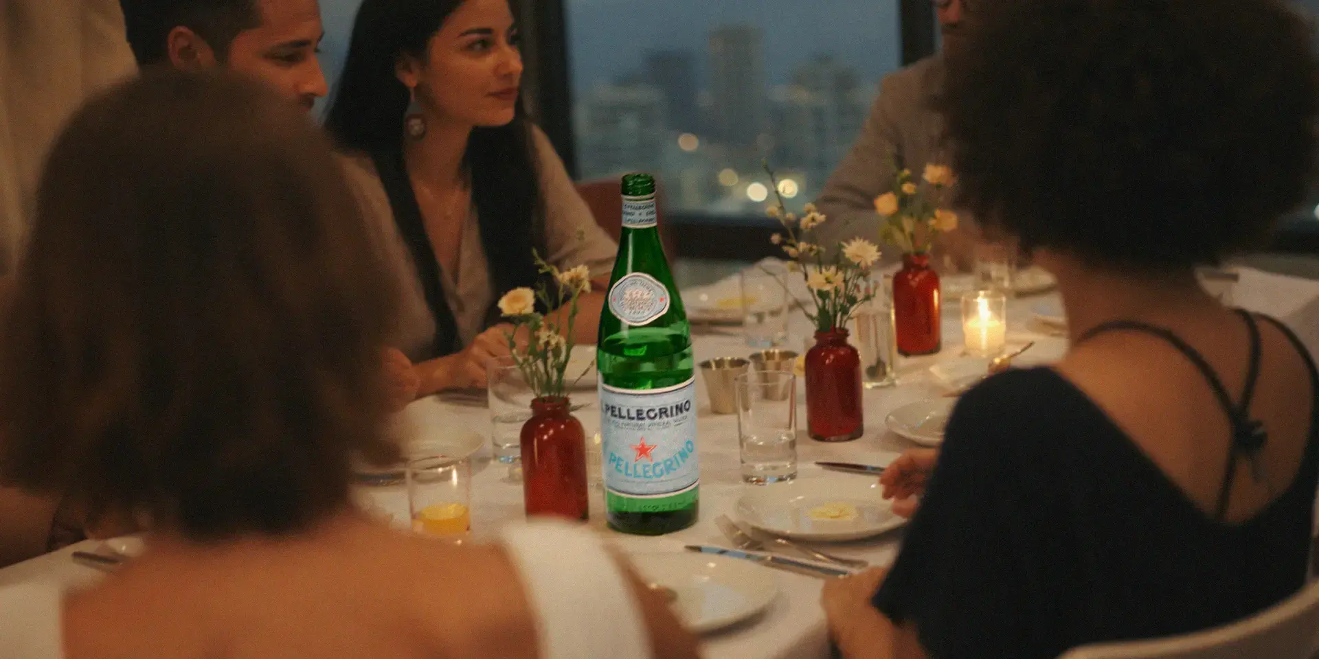 People around a dinner table, drinking S.Pellegrino.