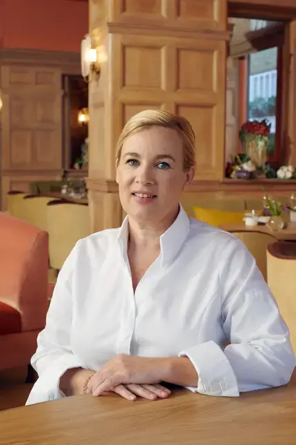 Chef Hélène Darroze sitting in a restaurant dining room.
