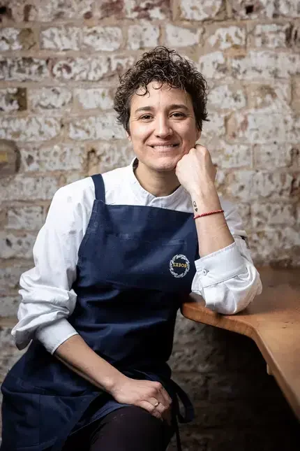 Chef Nieves Barragán Mohacho in front of a raw brick wall.