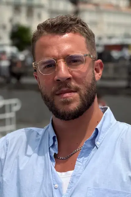 Jordon Ezra King in a blue shirt and glasses.