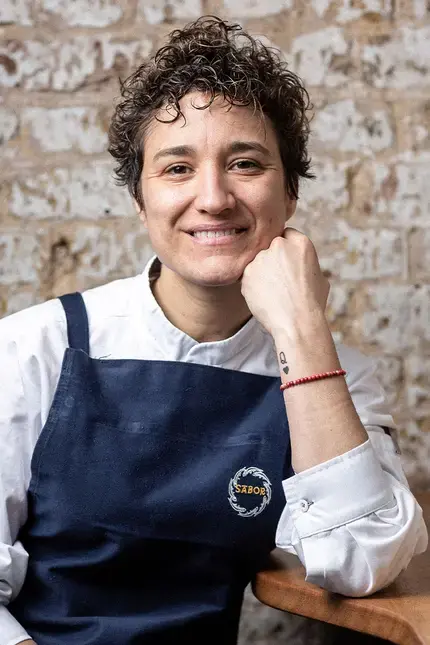 Chef Nieves Barragán Mohacho in front of a raw brick wall.