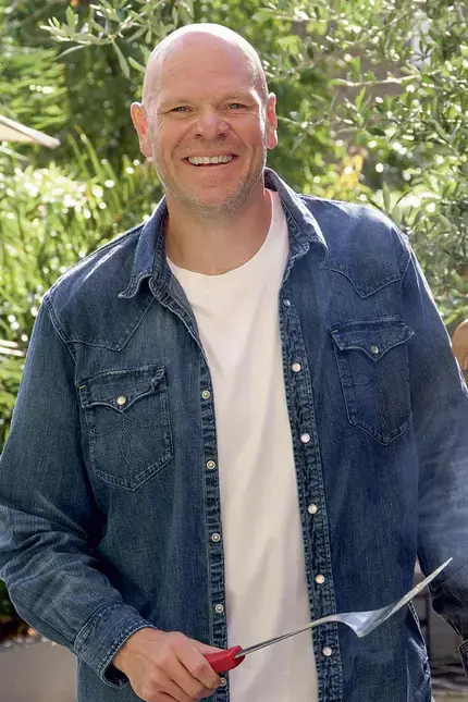 Chef Tom Kerridge standing next to a barbecue.