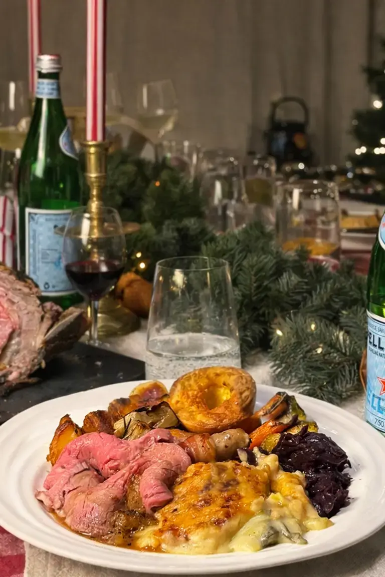 A roast beef dinner on a table with bottles of S.Pellegrino.