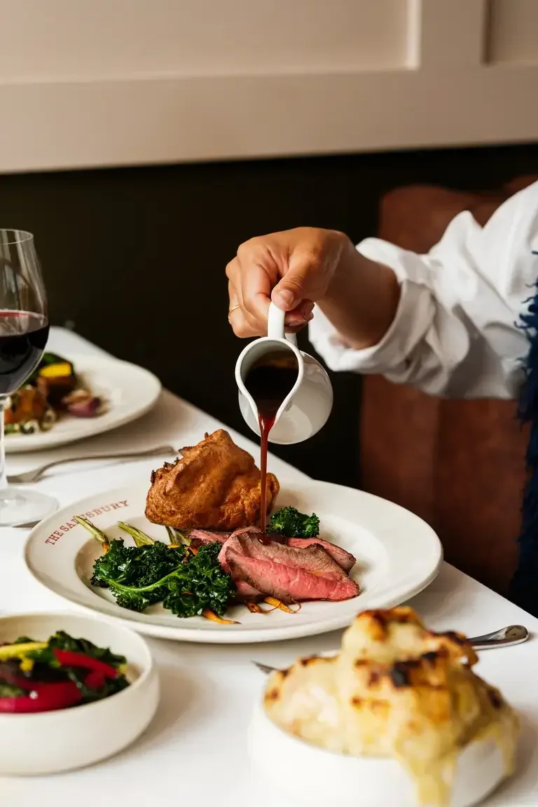 Someone pouring gravy on roast beef at The Salusbury.