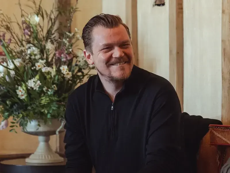 Chef Alex Dilling, seated and smiling in casual clothes.