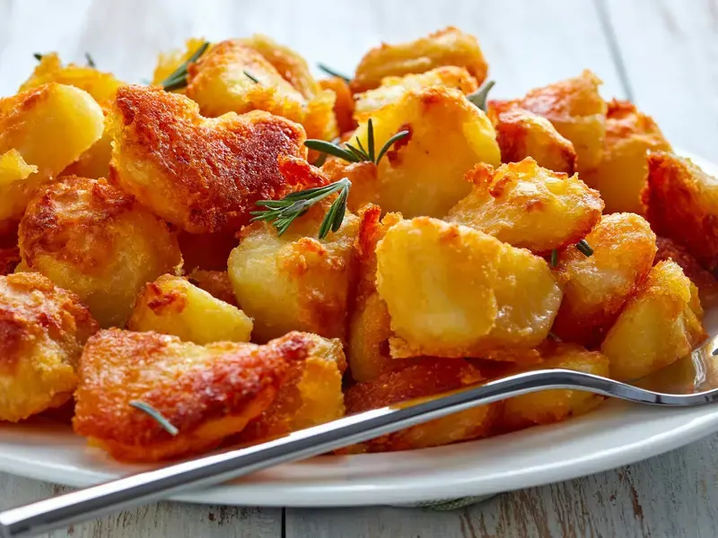 Crispy roast potatoes on a plate with a fork.