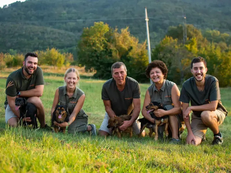 A family of five, each crouching with a small dog.