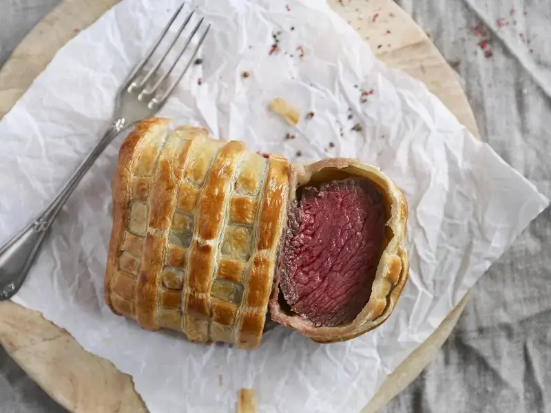 Beef Wellington, sliced on paper.