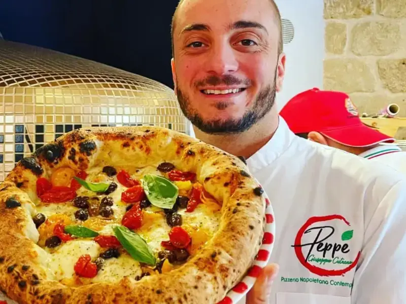 Peppe Cutraro holding up one of his pizzas