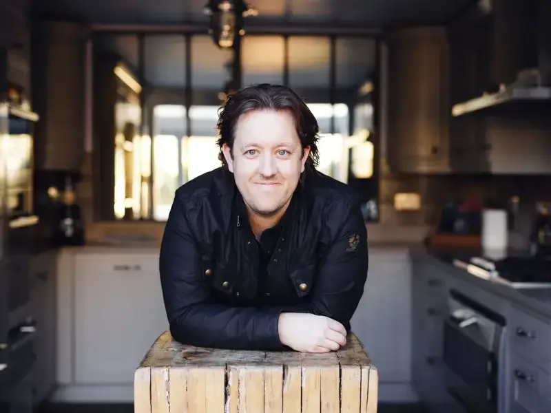 Chef Ashley Palmer-Watts leaning on a butcher's block.