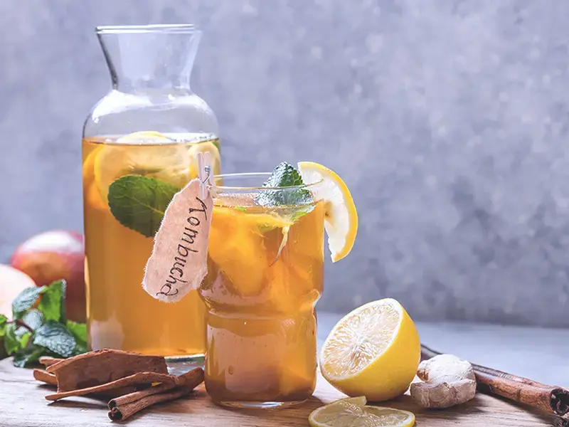 A carafe and glass of kombucha.