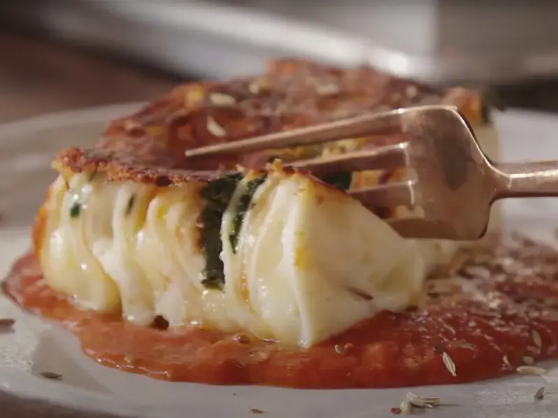 A fork cutting into a 24 layer lasanga on a plate