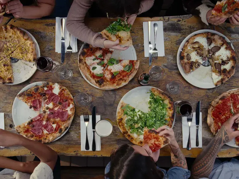 An overhead shot of people eating pizza at a table.