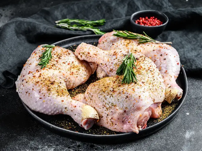Dish of chicken legs marinating with fresh herbs and spices.