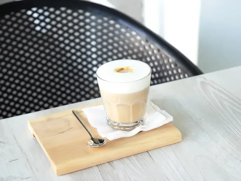 Flat white served with a teaspoon.