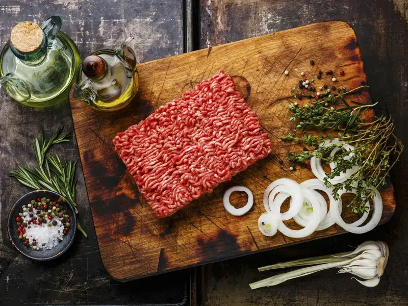 Ground beef and other ingredients on a board.