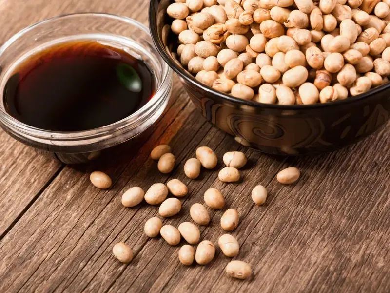A bowl of dark soy sauce with soy beans.
