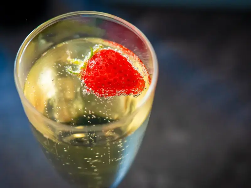 A glass of prosecco with a strawberry.