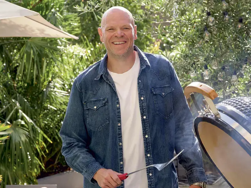 Chef Tom Kerridge standing next to a barbecue.