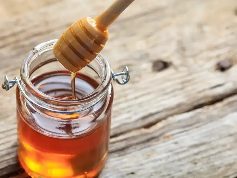a jar of open honey with a honey dipper