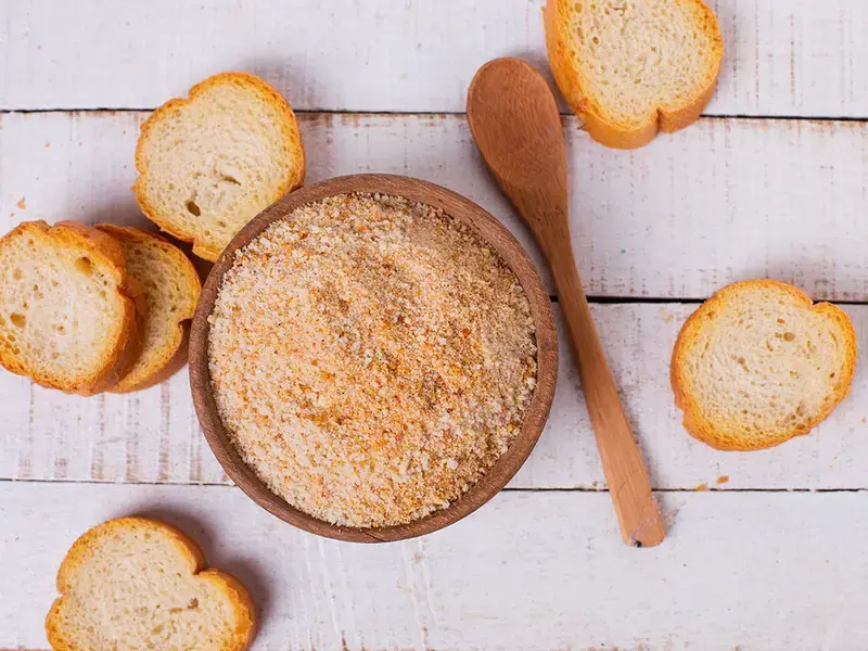Slices of stale bread and a bowl of breadcrumbs.