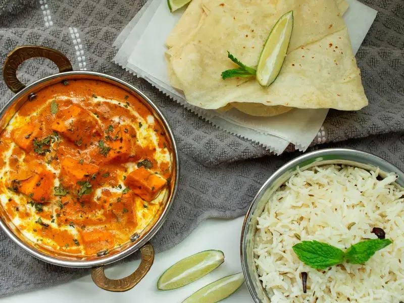 an overhead shot of a bowl of curry and rice and some poppadoms