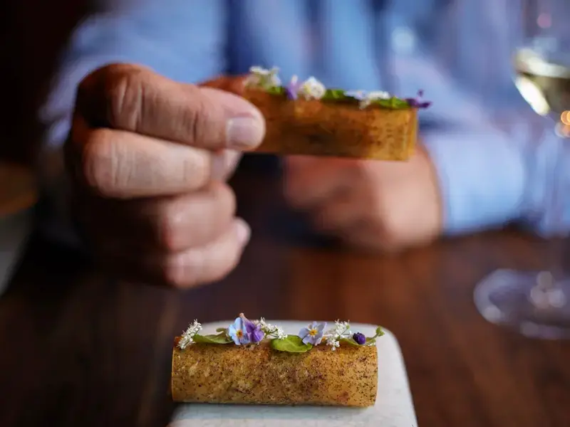a hand picking up an amuse bouche in a fine dining restaurant