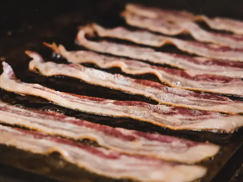 Rashers of bacon cooking