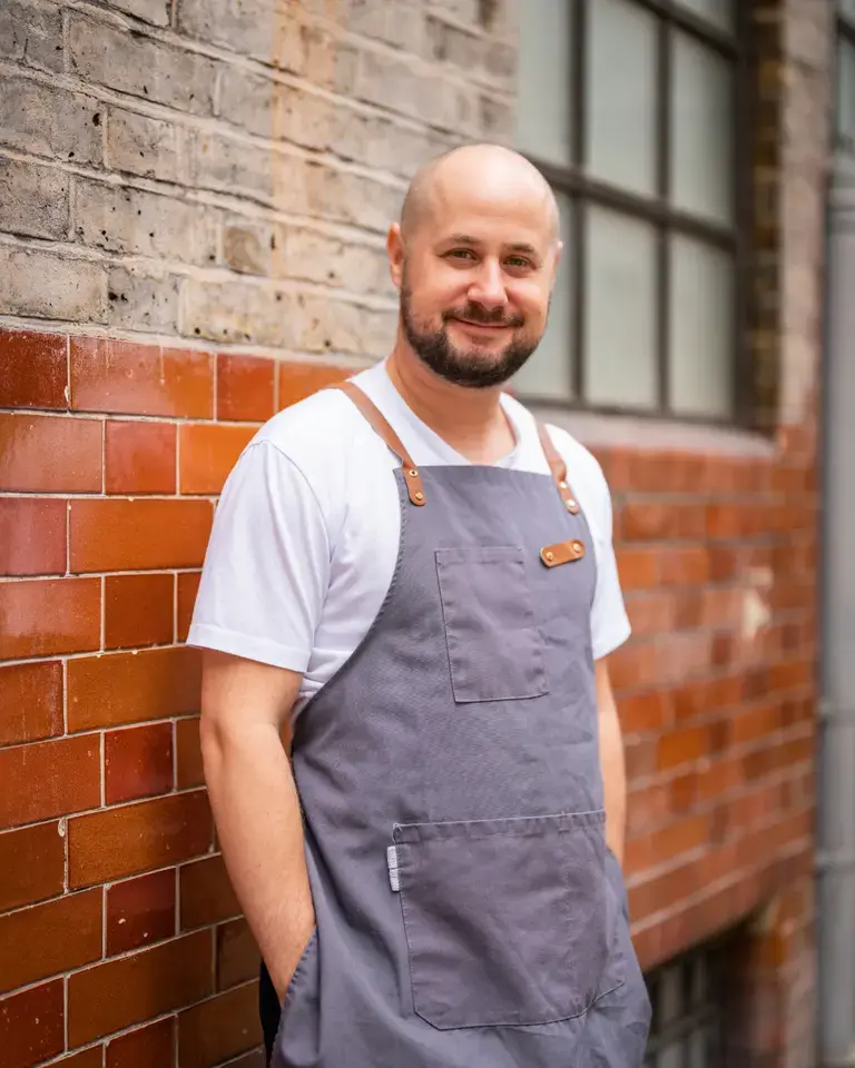 Chef Tom Cenci standing against a wall.