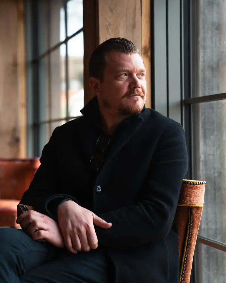 Chef Alex Dilling seated, looking out of a window.