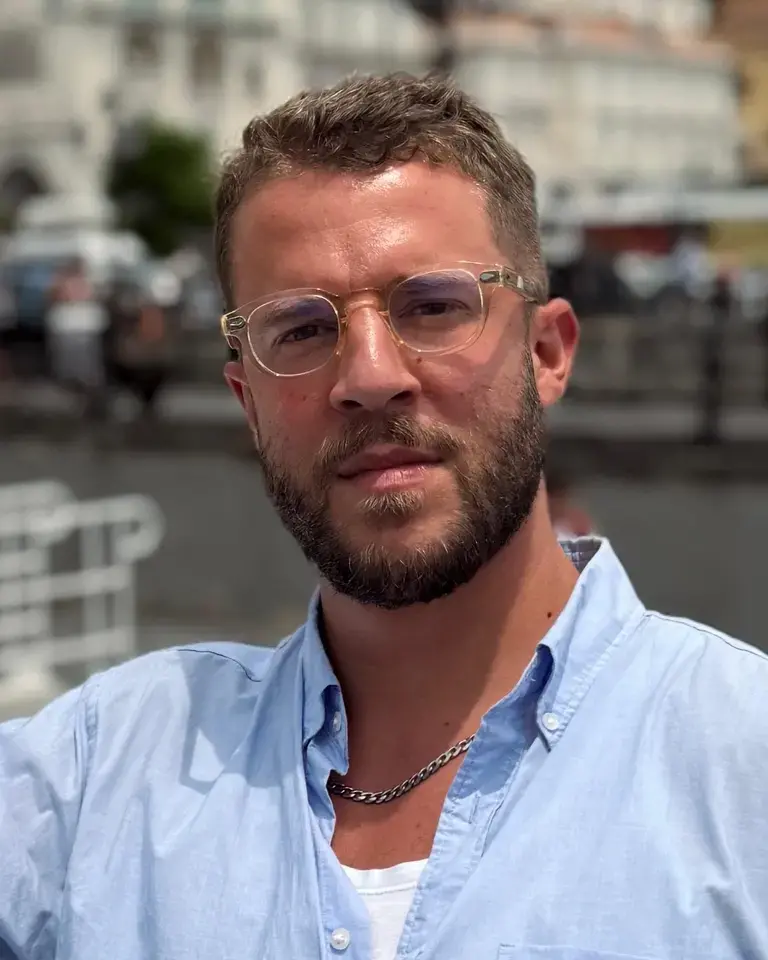 Jordon Ezra King in a blue shirt and glasses.