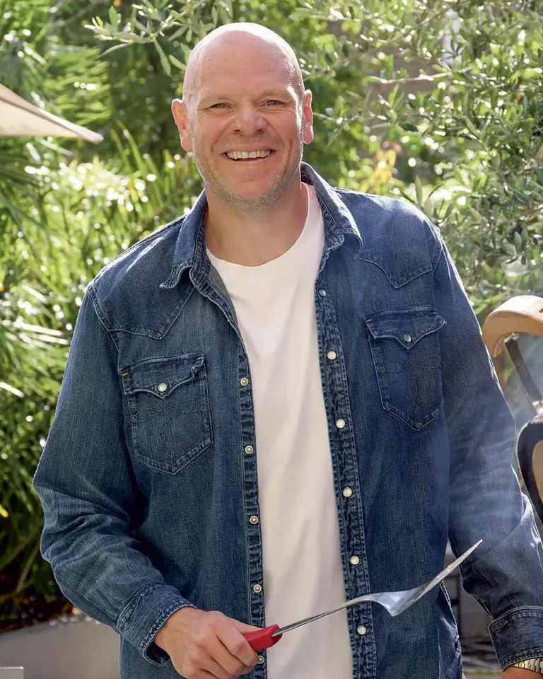 Chef Tom Kerridge standing next to a barbecue.