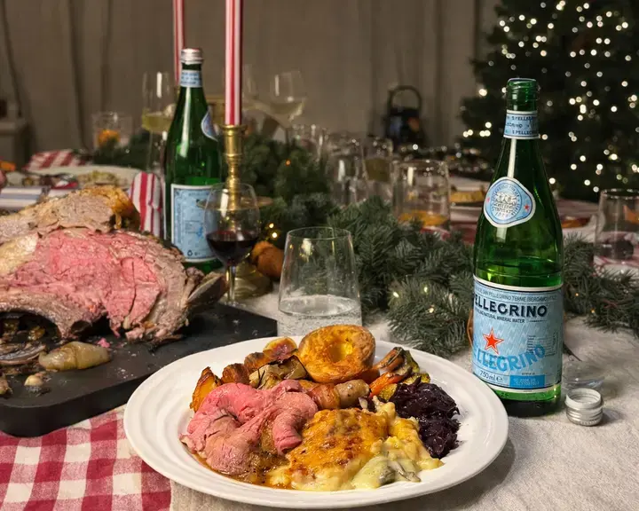 A roast beef dinner on a table with bottles of S.Pellegrino.