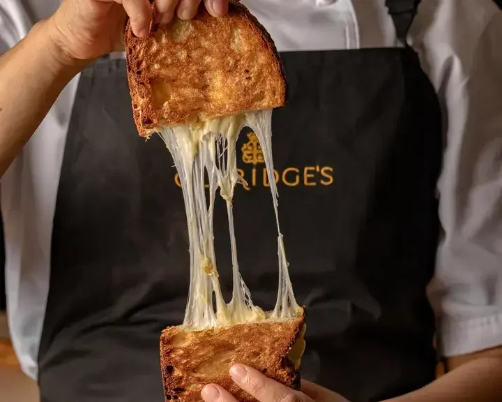 Someone pulling apart a toastie at Claridge's Bakery.