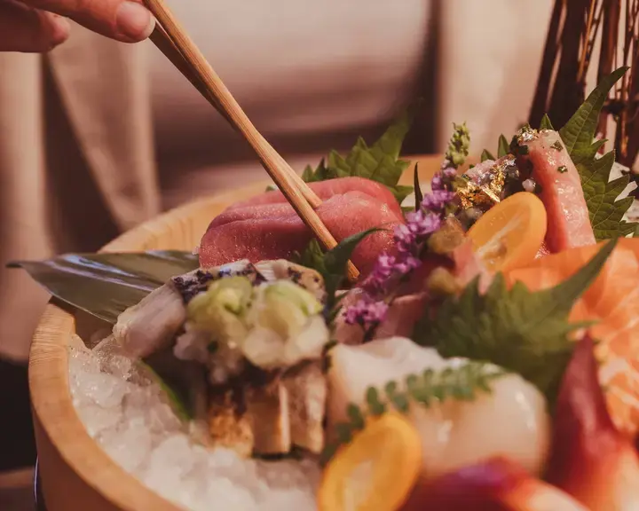 A woman eating sashimi with chopsticks at Yamato.